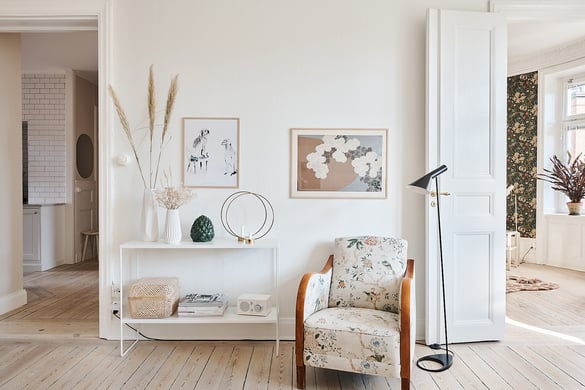 hall i sekelskifteslägenhet med stoppad fåtölj och avlastningsbord