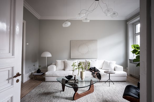 vardagsrum med stor vit soffa och glasbord