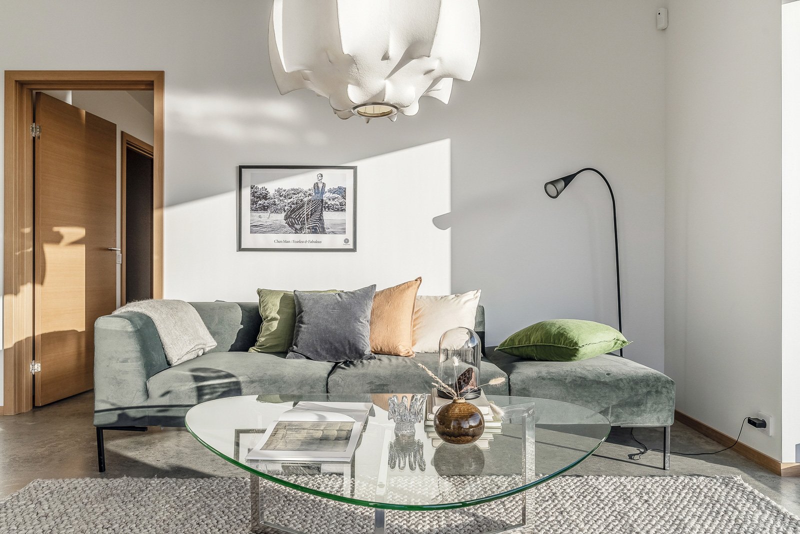 Rum efter homestaging: En ljust grå soffa i sammetsmaterial, matta, tavla, soffbord och tavla på väggen. 
