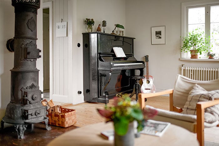 Vardagsrum med kamin och piano i ett hus på landet