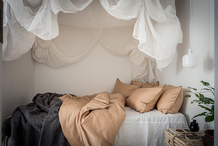 En mysig säng med sänghimmel i en studentlägenhet, där föräldrar har hjälpt till att köpa bostad till sina barn.