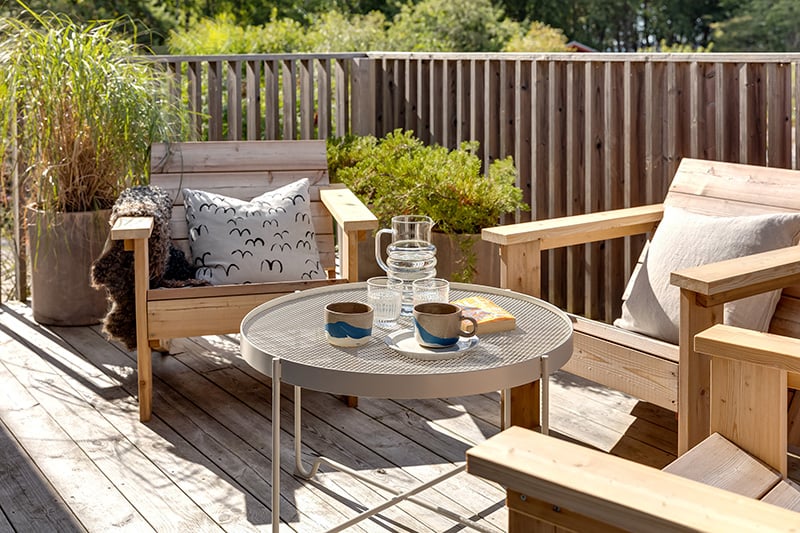 Uteplats inspiration: en solig altan med träfåtöljer, ett uppdukat cafébord och gröna krukväxter